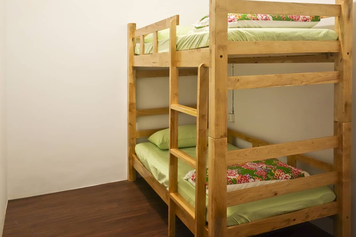 A bunk bed with green bedding and floral-patterned pillows.