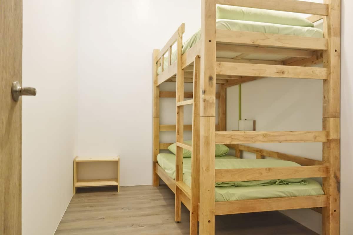 A bunk bed room with a wooden door and a small shelf.