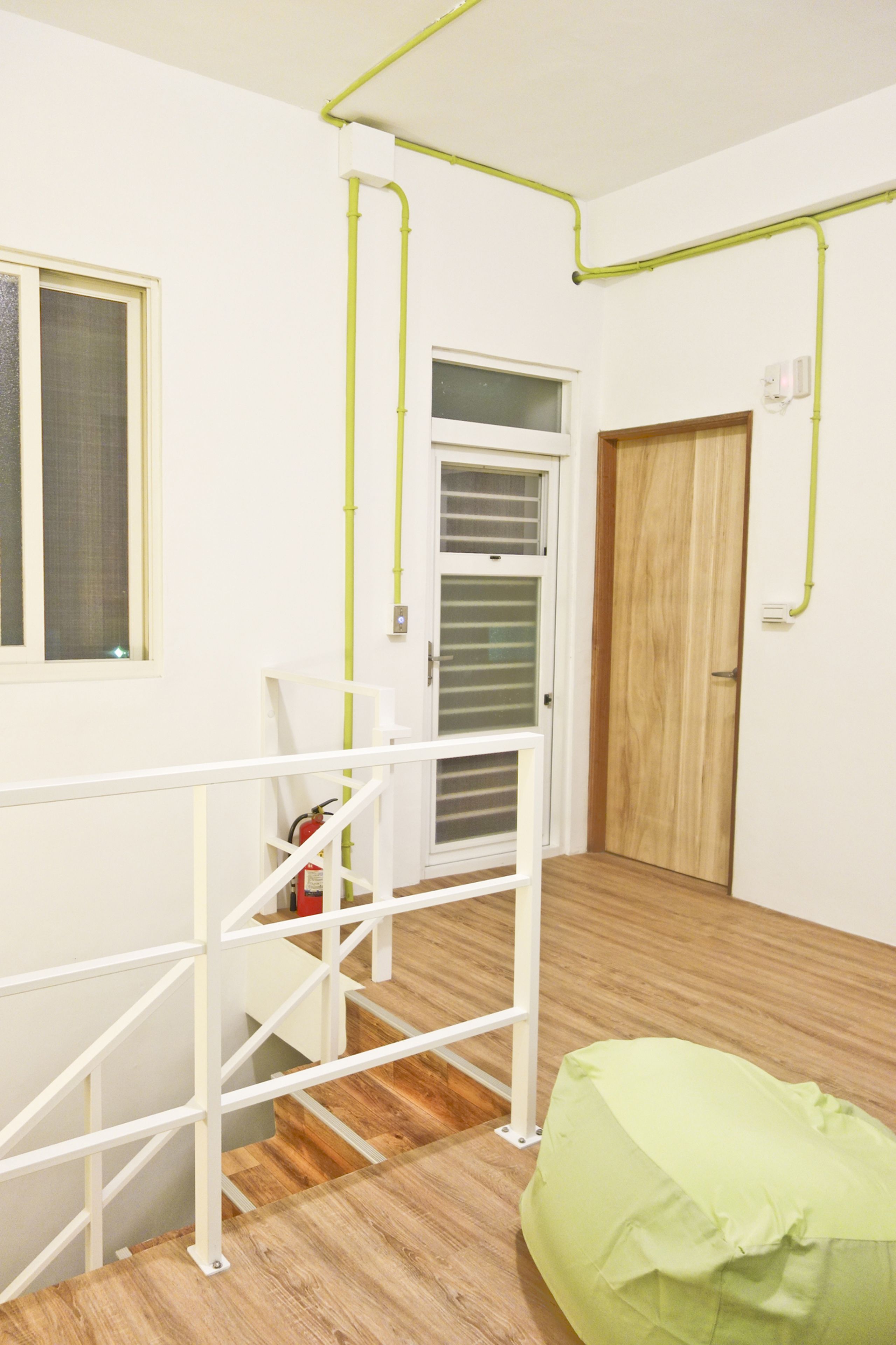 Una habitación con una escalera, una puerta de madera y un sillón de cuero tipo frijol verde.