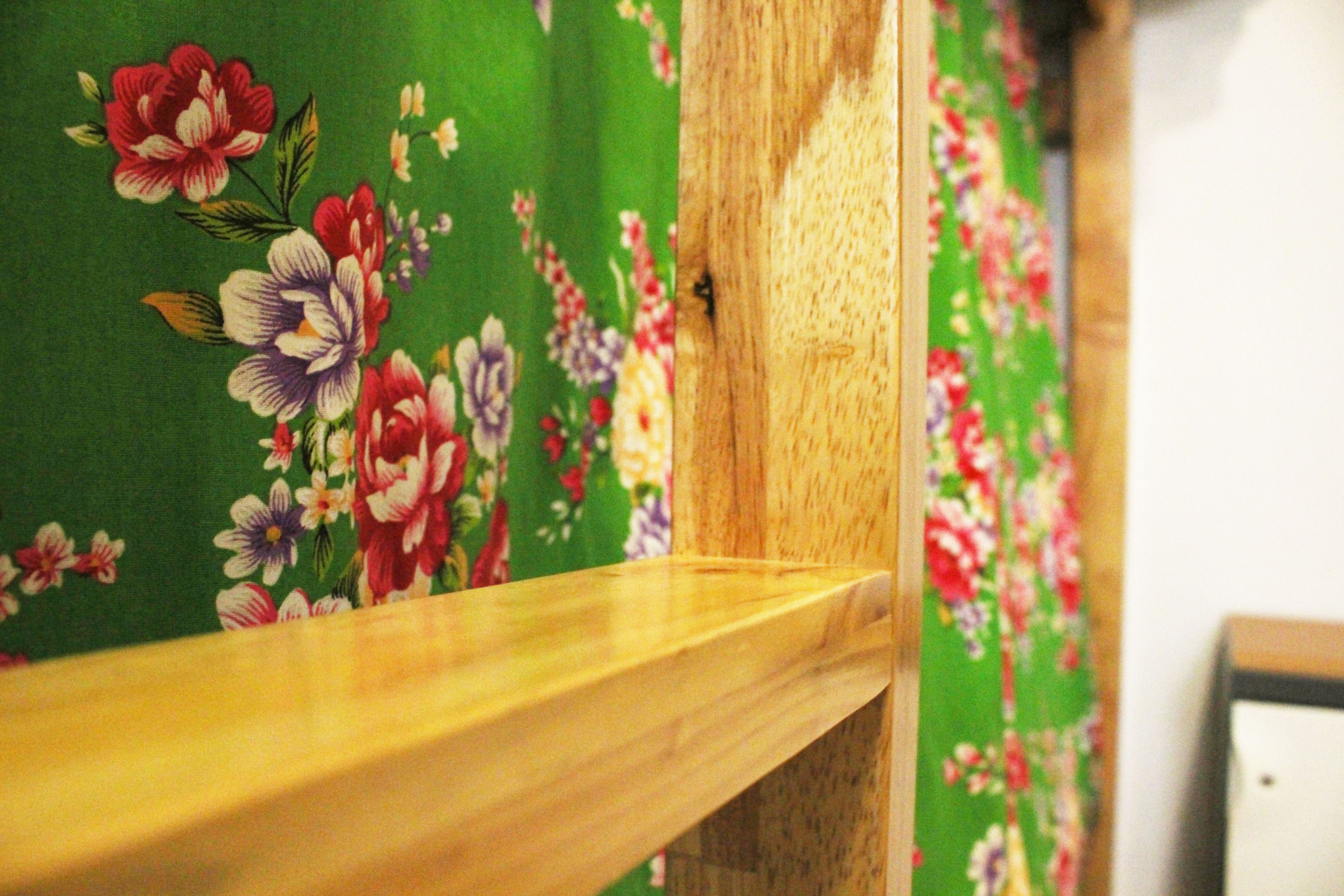 A wooden railing with a floral-patterned fabric backdrop.