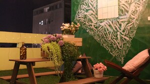 Un área de estar al aire libre con una mesa de picnic, sillas y luces colgantes.