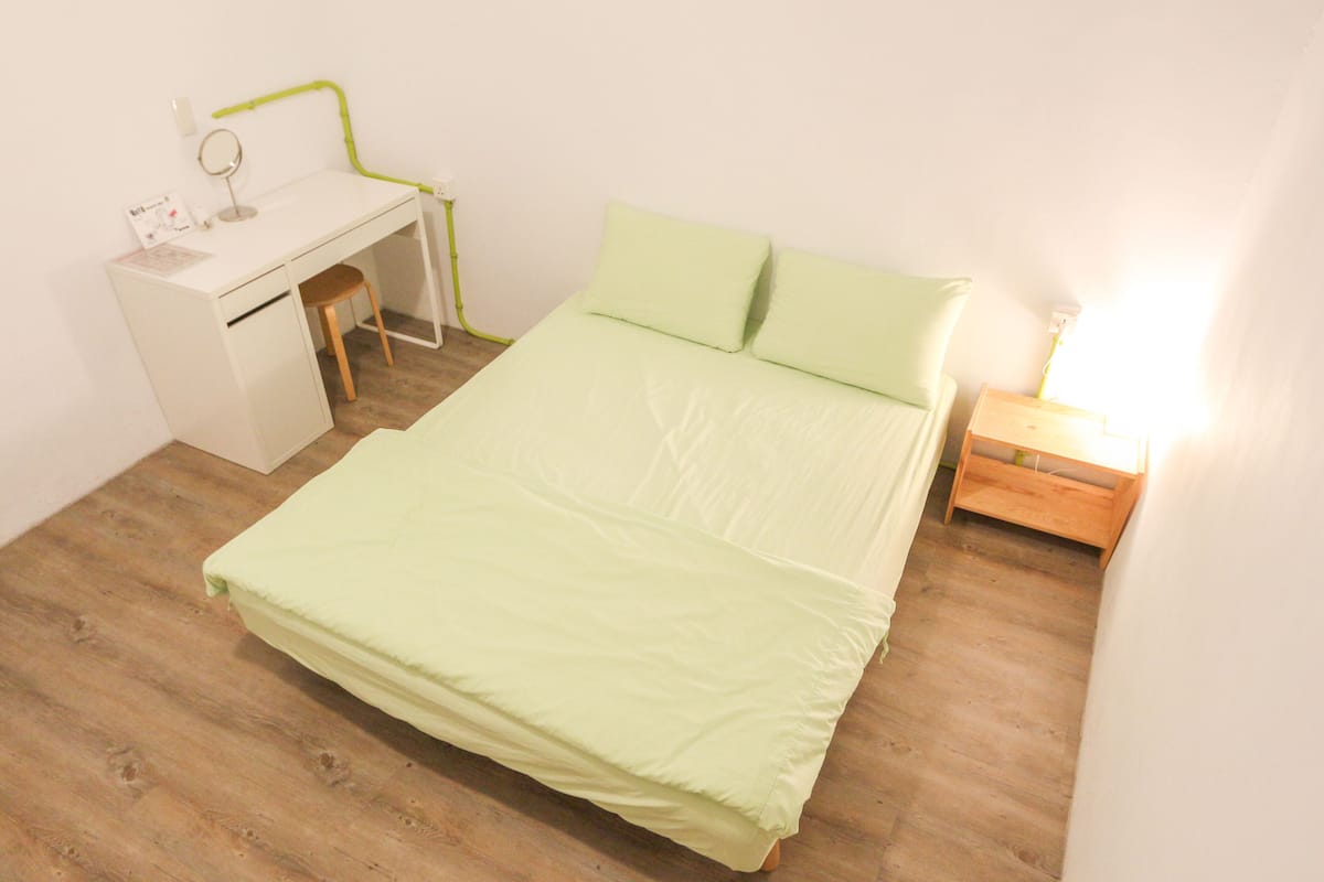 A bedroom with a bed, a desk, and a chair.