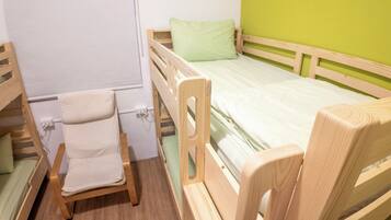A room with a bunk bed, a single bed, and a chair.