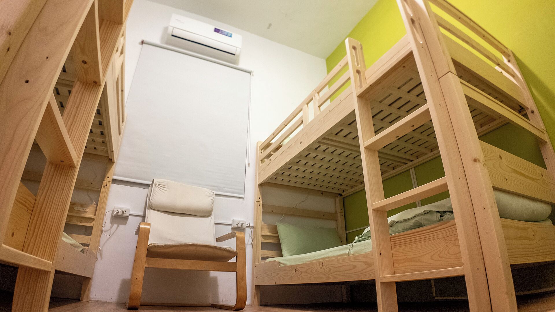 A bunk bed room with a chair and an air conditioning unit.