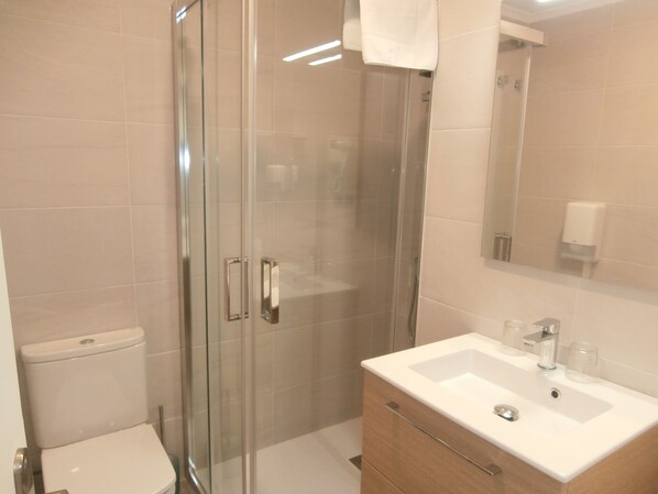 A modern bathroom with a glass shower enclosure, a white sink, and a wooden vanity.