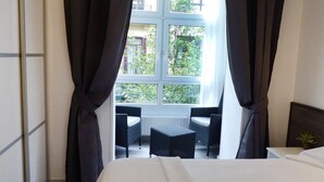 A hotel room with a bed, a window with curtains, and a small balcony with two chairs and a table. - Pensión Donostiarra (San Sebastián)