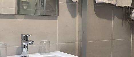 Baño con lavamanos, espejo, toallero y secador de manos.