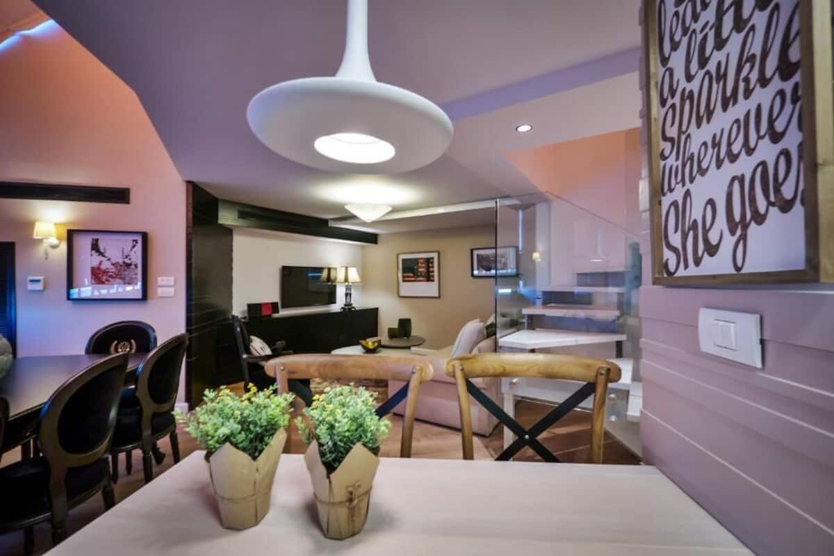 Ein modernes Wohnzimmer mit Essbereich, Fernseher und Treppe.