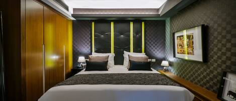 A hotel room with a large bed, two bedside tables with lamps, a wardrobe, and a checkered wall pattern.