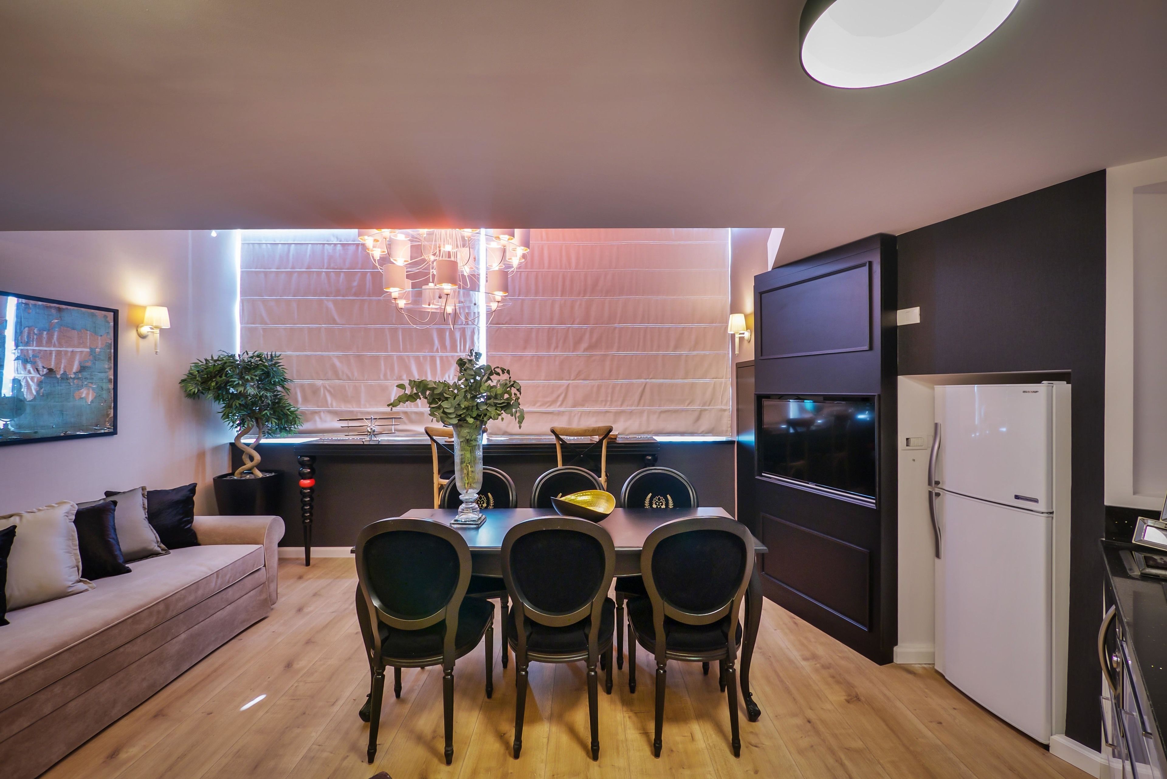 A modern kitchen with a dining table, chairs, and a refrigerator.