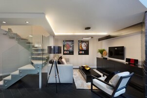 Una sala de estar moderna con una escalera, un sofá, una mesa de centro y un televisor.