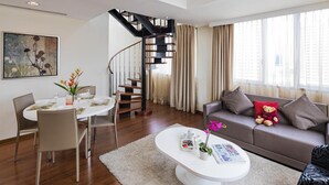 Ein modernes Wohnzimmer mit Essbereich, einer Treppe und einem Sofa mit Kissen.