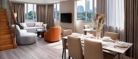 A modern living room with a sofa, dining table, and chairs, a staircase, and a city view.