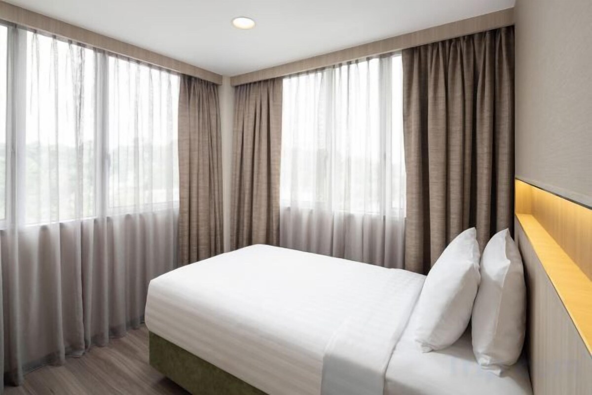 Ein Hotelzimmer mit Bett, Vorhängen und Kopfteil.