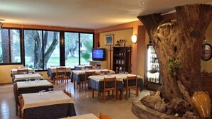 Un ristorante con diversi tavoli e sedie, una televisione, una libreria e una grande decorazione con un tronco d'albero.