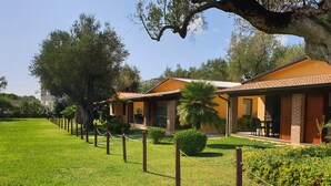 Una fila di edifici a due piani con facciate in mattoni e tetti arancioni, circondati da prati curati e alberi.