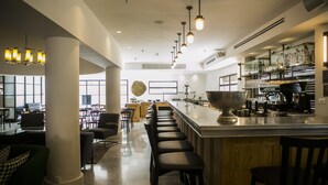 A modern bar area with a long counter, multiple stools, and a large bar sink. - Lily & Bloom Hotel (Tel Aviv)