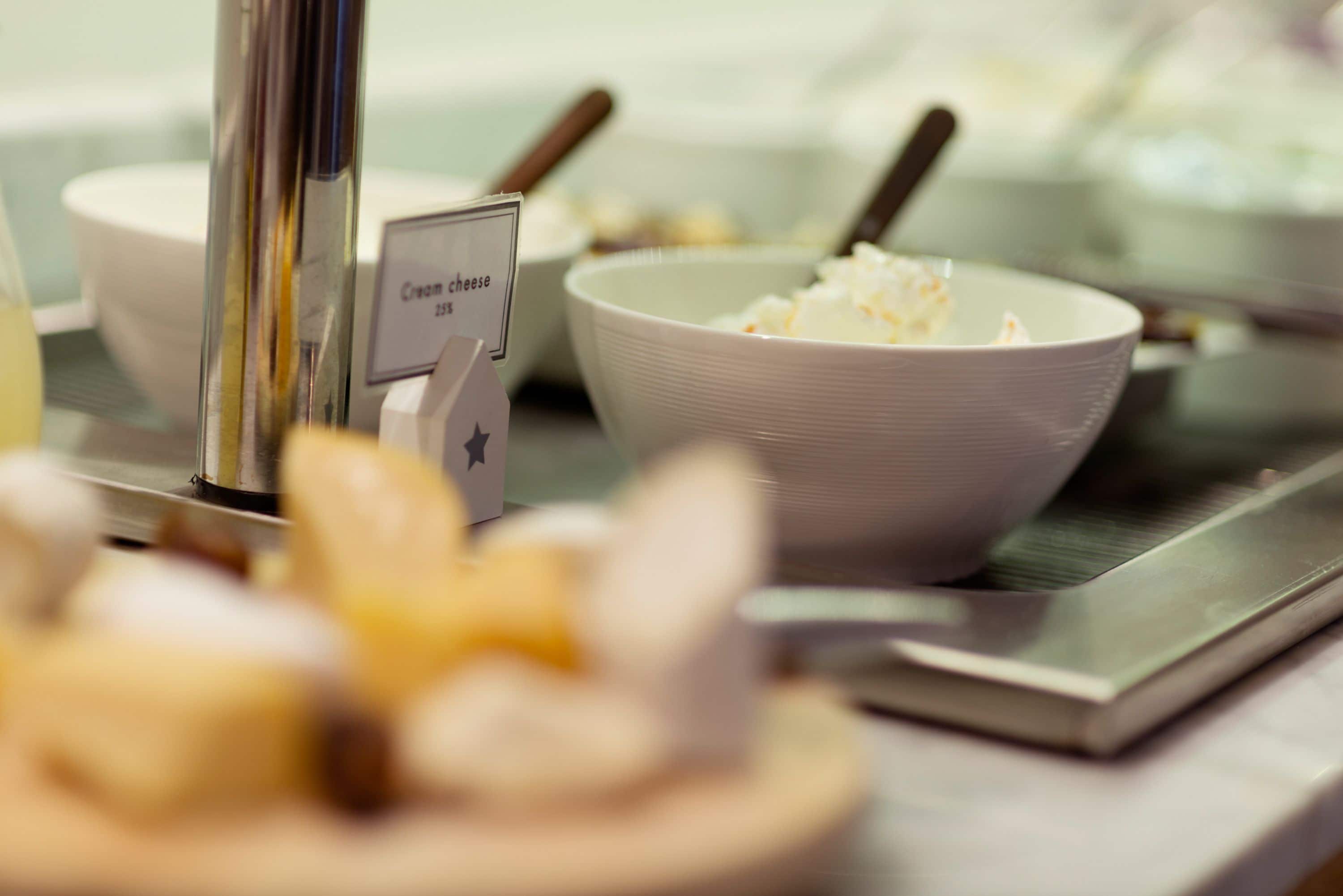 Ein Buffet mit Schalen, gefüllt mit Frischkäse und weiteren Speisen.
