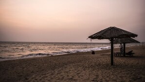 Une plage avec un parasol en chaume et des bancs.