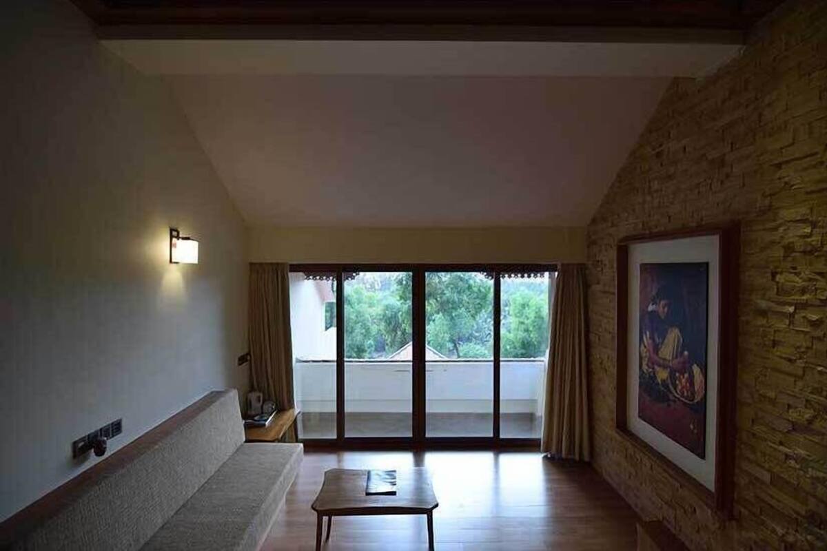 A room with a large sliding glass door leading to a balcony, a sofa, a small table, and a framed picture on the wall.