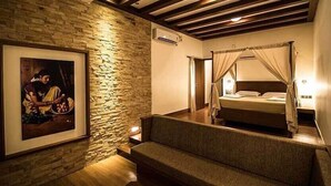 Une chambre avec un mur en pierre, un lit à baldaquin, un canapé et un tableau encadré accroché au mur.