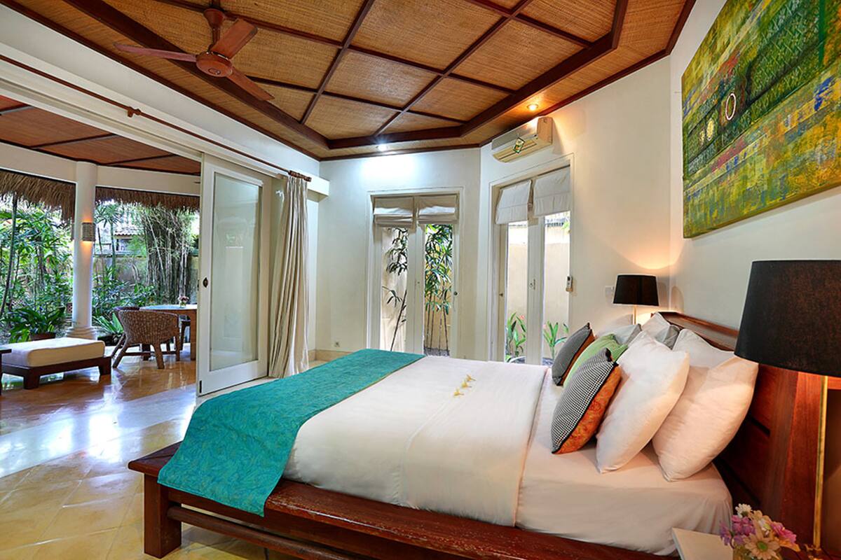 A spacious bedroom with a large bed, a ceiling fan, and a view of the outdoors.
