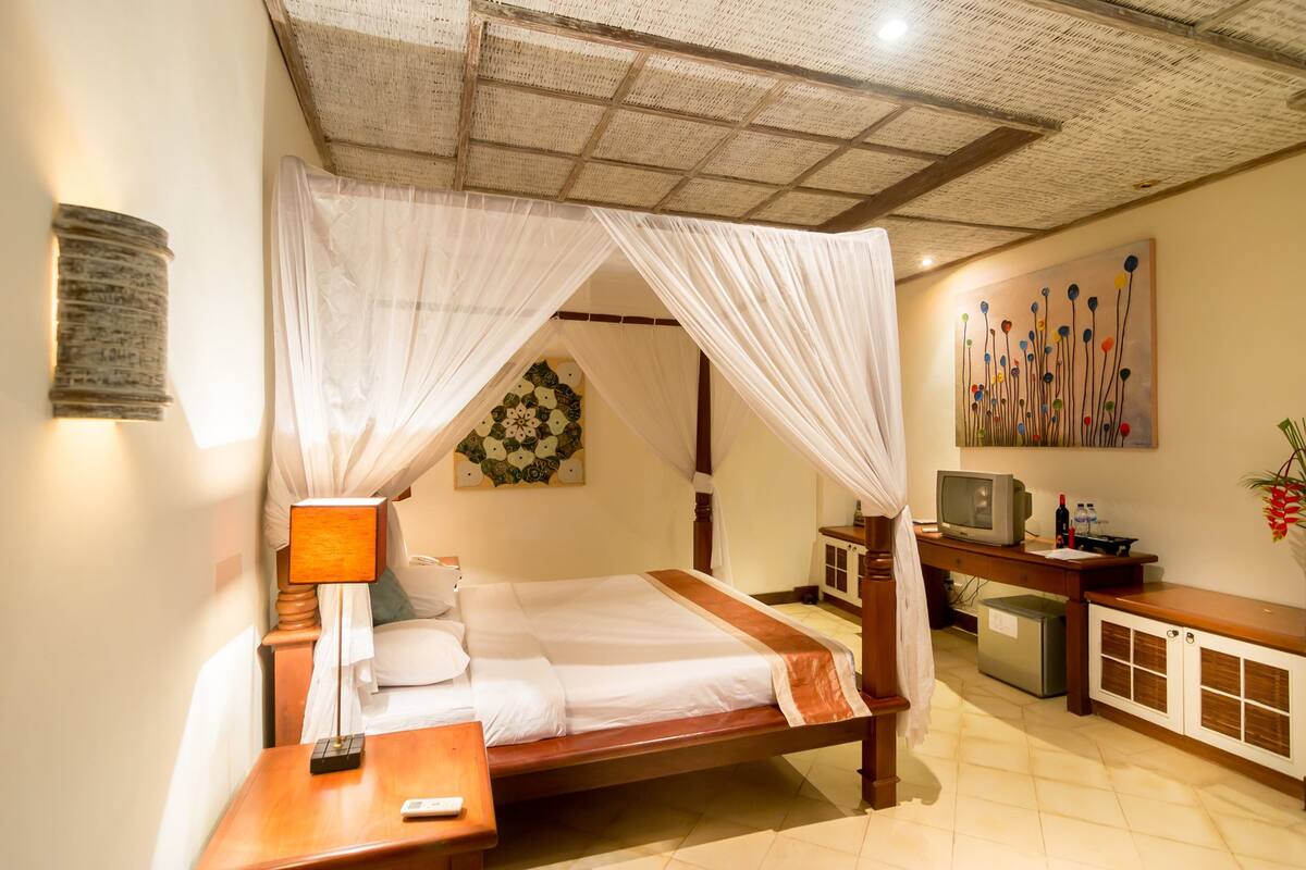 A bedroom with a bed, bedside table, TV, and a desk with a computer.