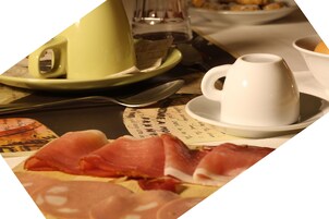 Une table avec une assiette de charcuterie, un verre vert et un verre blanc.