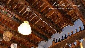 A kitchen with wooden beams, shelves with kitchenware, and a microwave. - Abatellis Luxury (Palermo)