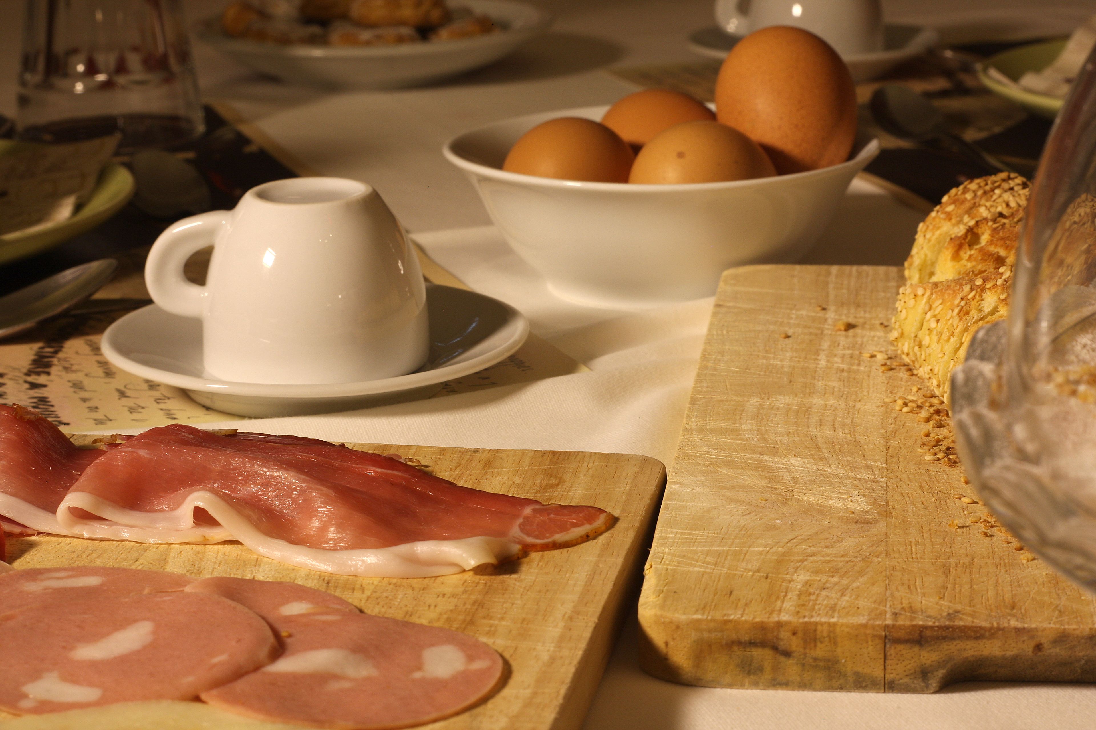 Un desayuno con tabla de cortar, jamón, huevos y pan.