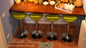 A kitchen with a wooden ceiling, a fruit display, and green bar stools. - Abatellis Luxury (Palermo)