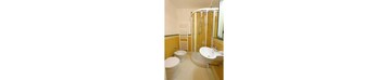 Un bagno con due servizi igienici, un lavandino e una cabina doccia.