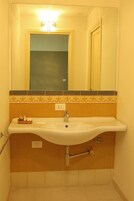 Un bagno con lavandino, specchio e portasciugamani.