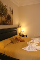 Una camera d'albergo con un letto, un comodino con una lampada e un quadro appeso al muro.