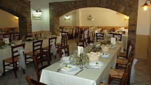 Un restaurante con varias mesas dispuestas para comer, arcos de piedra y piso de baldosas.