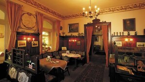Una habitación tradicional con chimenea, candelabro y zona de comedor.