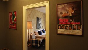 Una habitación de hotel con una cama, una silla, una lámpara y un cartel en la pared.