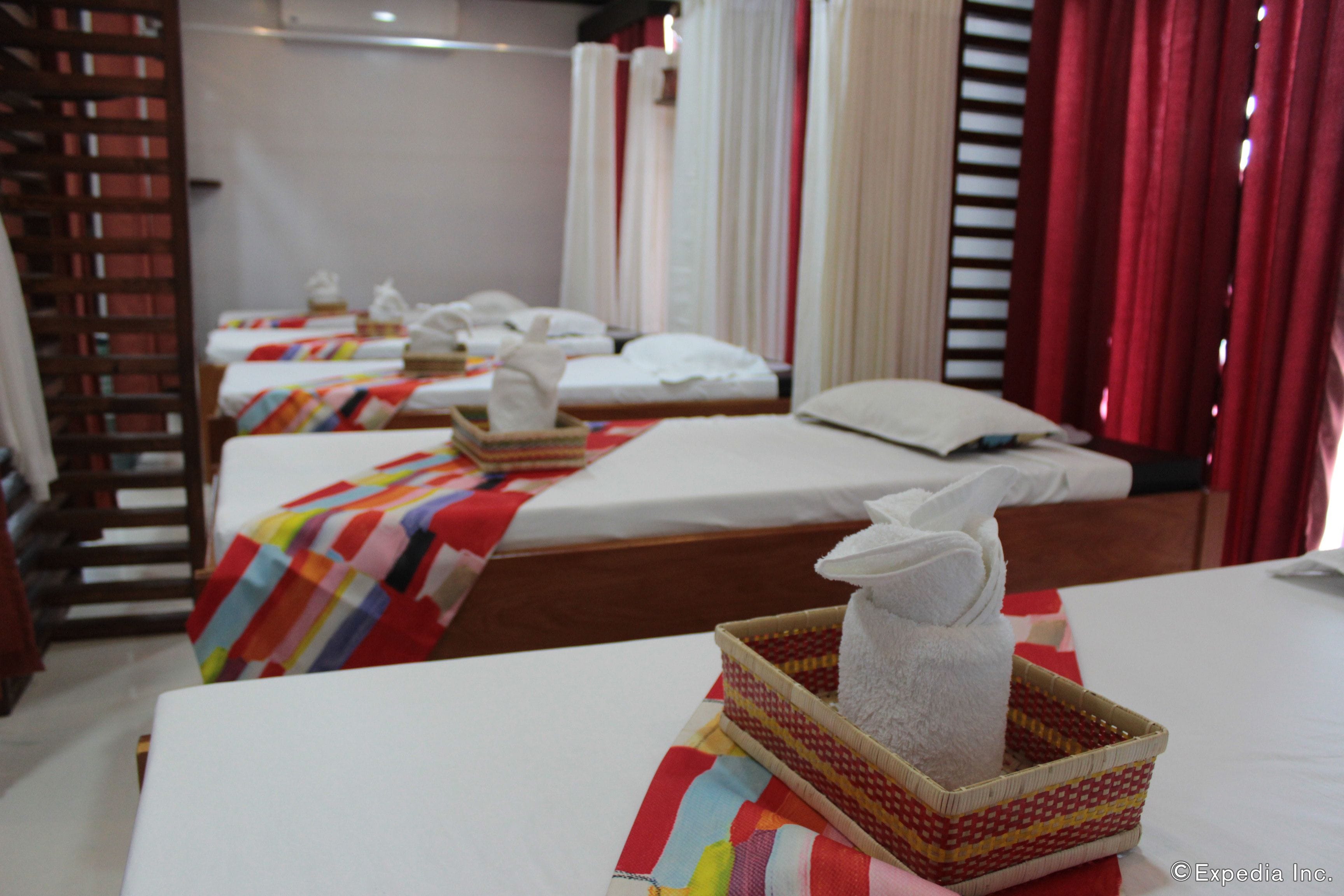 A hotel room with two beds, each with a colorful striped blanket and a white pillow. There is a small woven basket with a towel on the bed in the foreground.