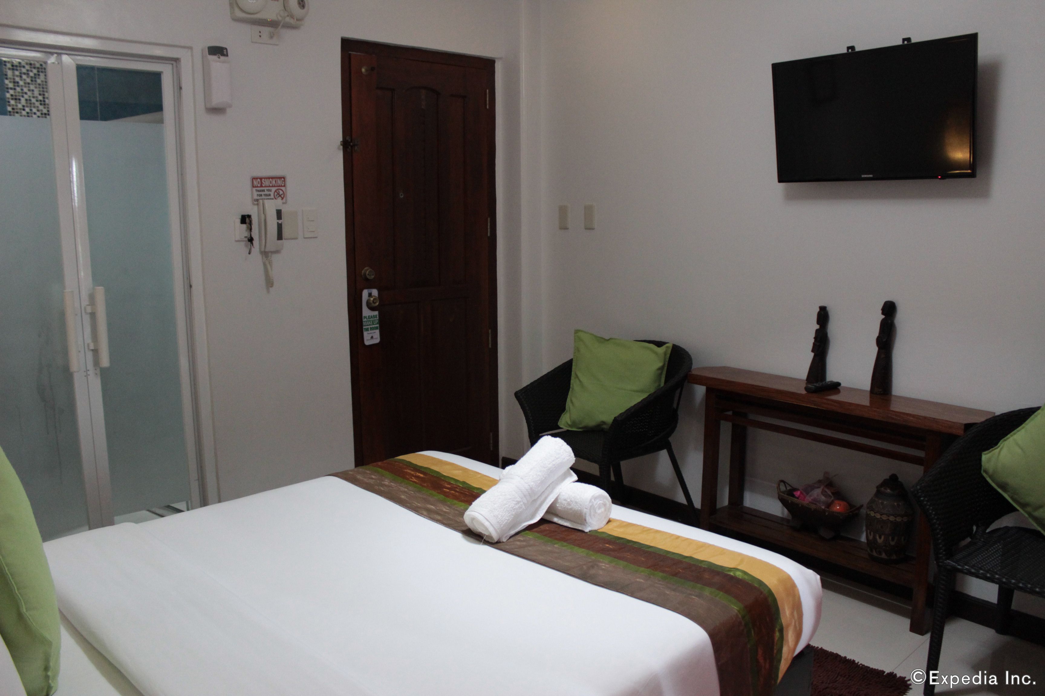 Una habitación de hotel con una cama, un escritorio, una silla, un televisor y una puerta.