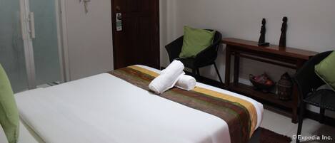 Una habitación de hotel con una cama, un escritorio, una silla, un televisor y una puerta.