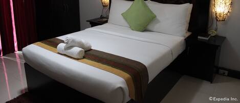 A neatly made bed with a green pillow, white linens, and a striped bedspread. There are two bedside tables with lamps, a dark headboard, and a wardrobe in the background.
