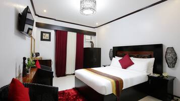 A modern bedroom with a bed, bedside tables, a desk, and a chair.