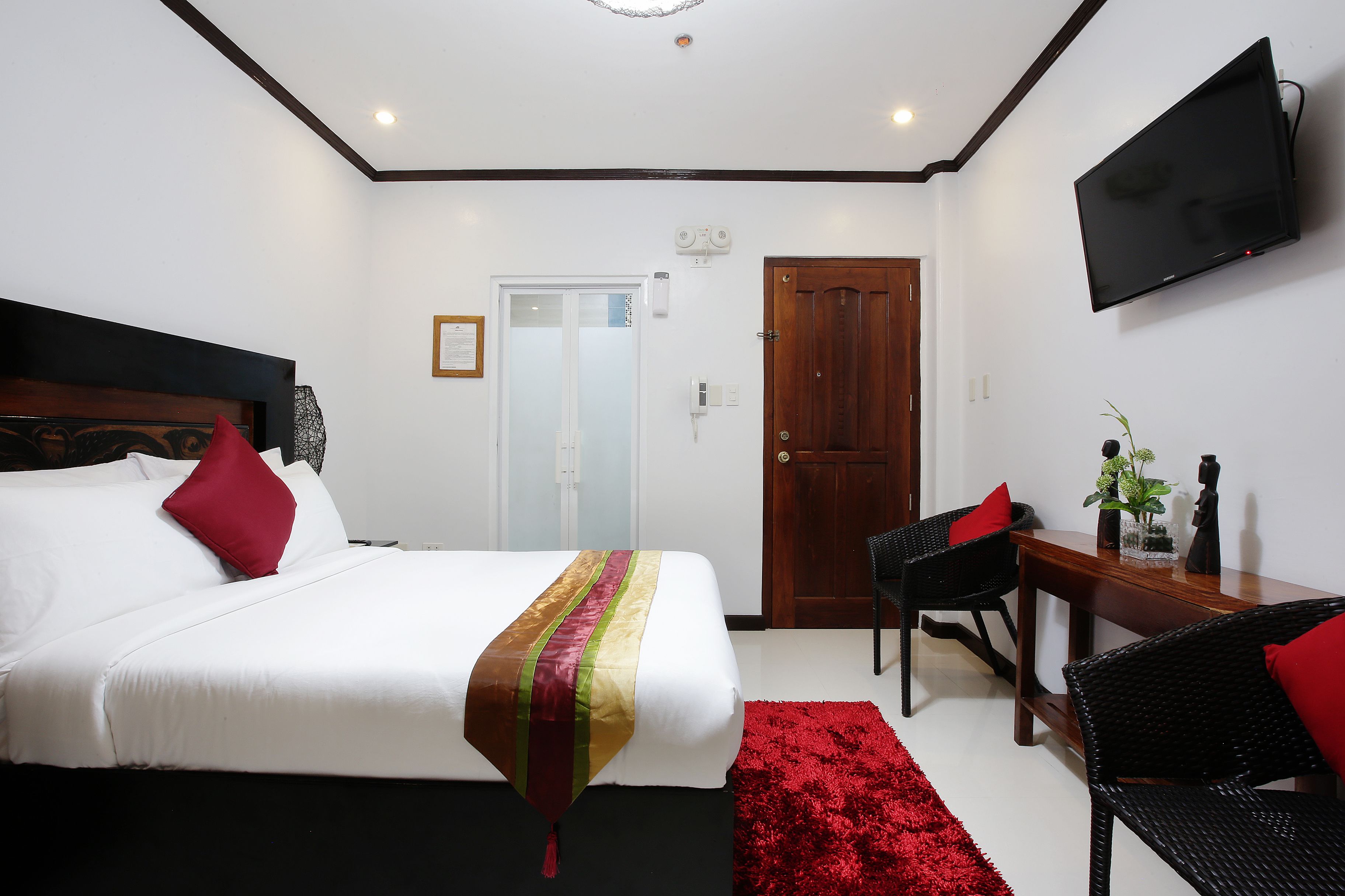 A hotel room with a bed, a desk, a chair, a TV, and a door.