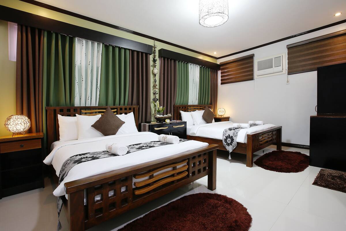 A modern bedroom with two wooden beds, a large mirror, and a TV.