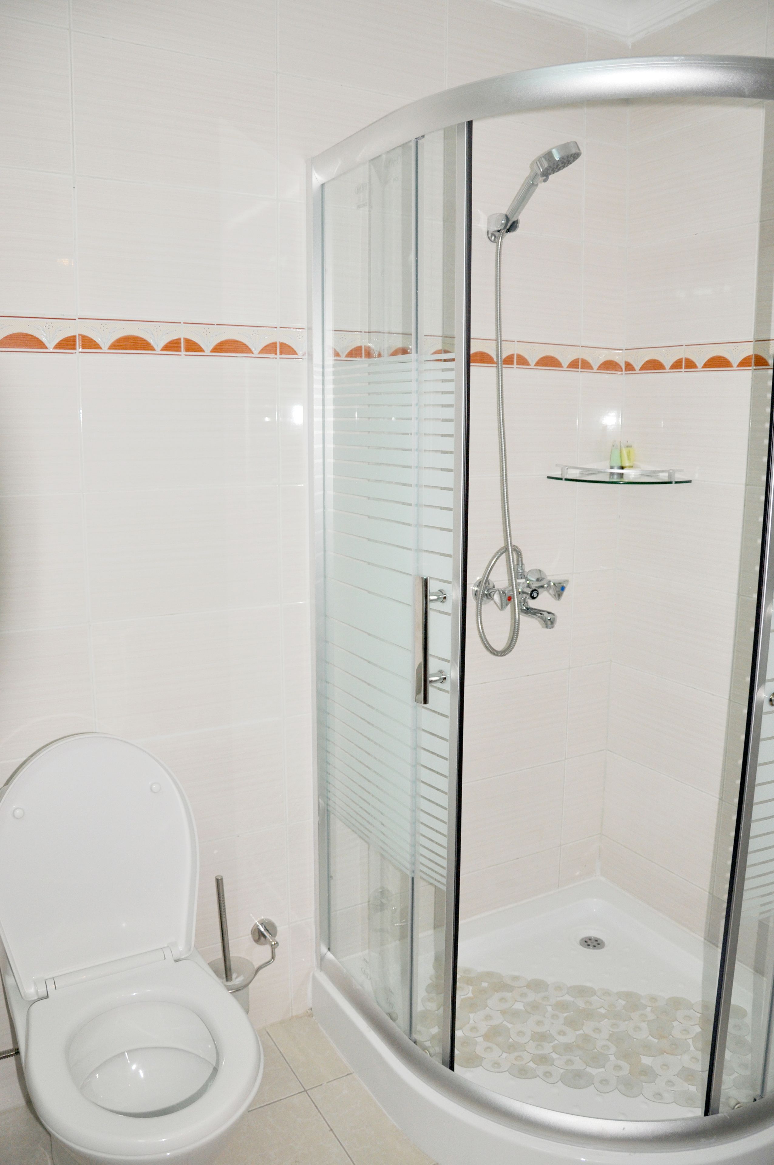Un baño con ducha de vidrio, inodoro y suelo de baldosas.