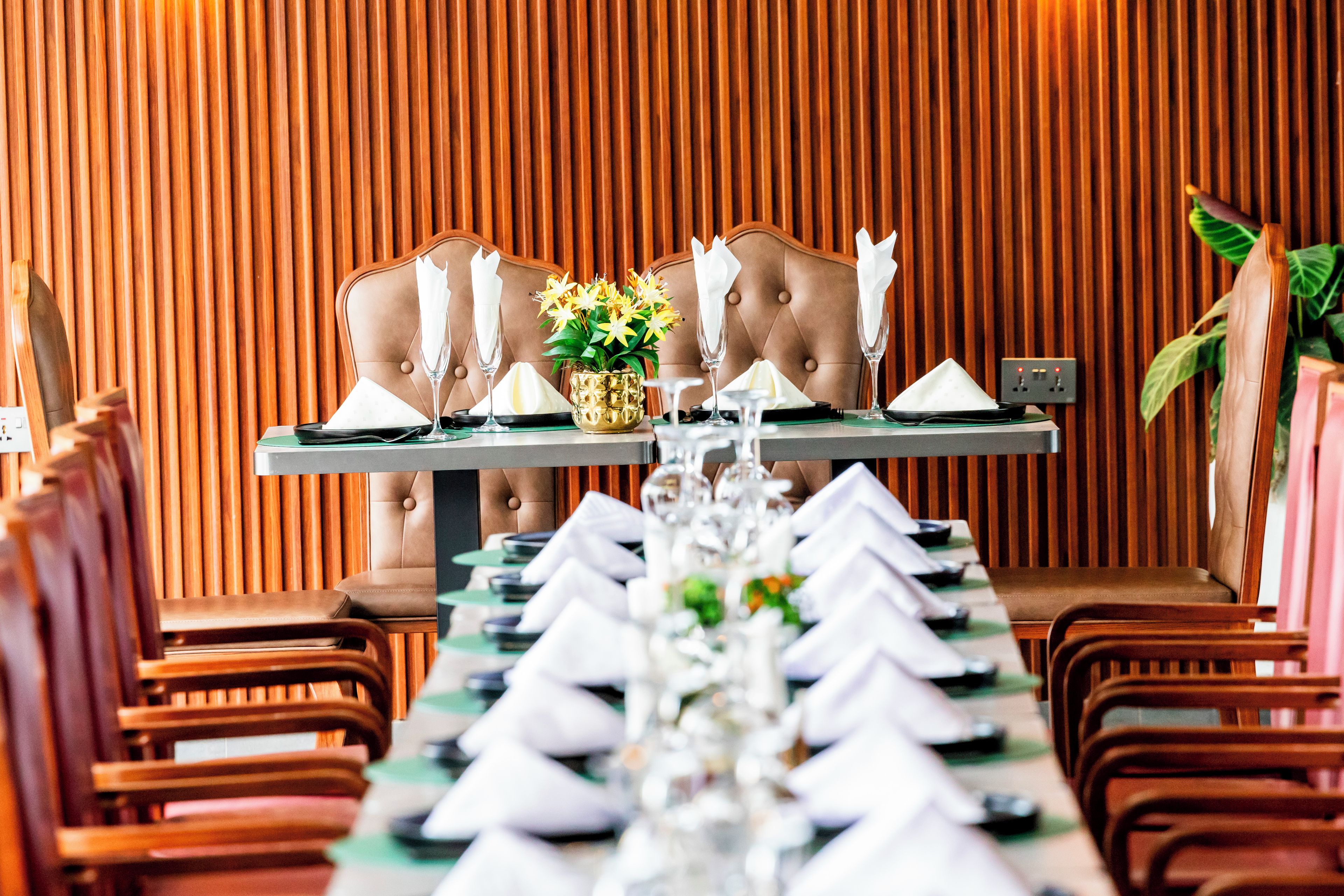 A dining table set with white napkins, a centerpiece, and a vase of flowers.