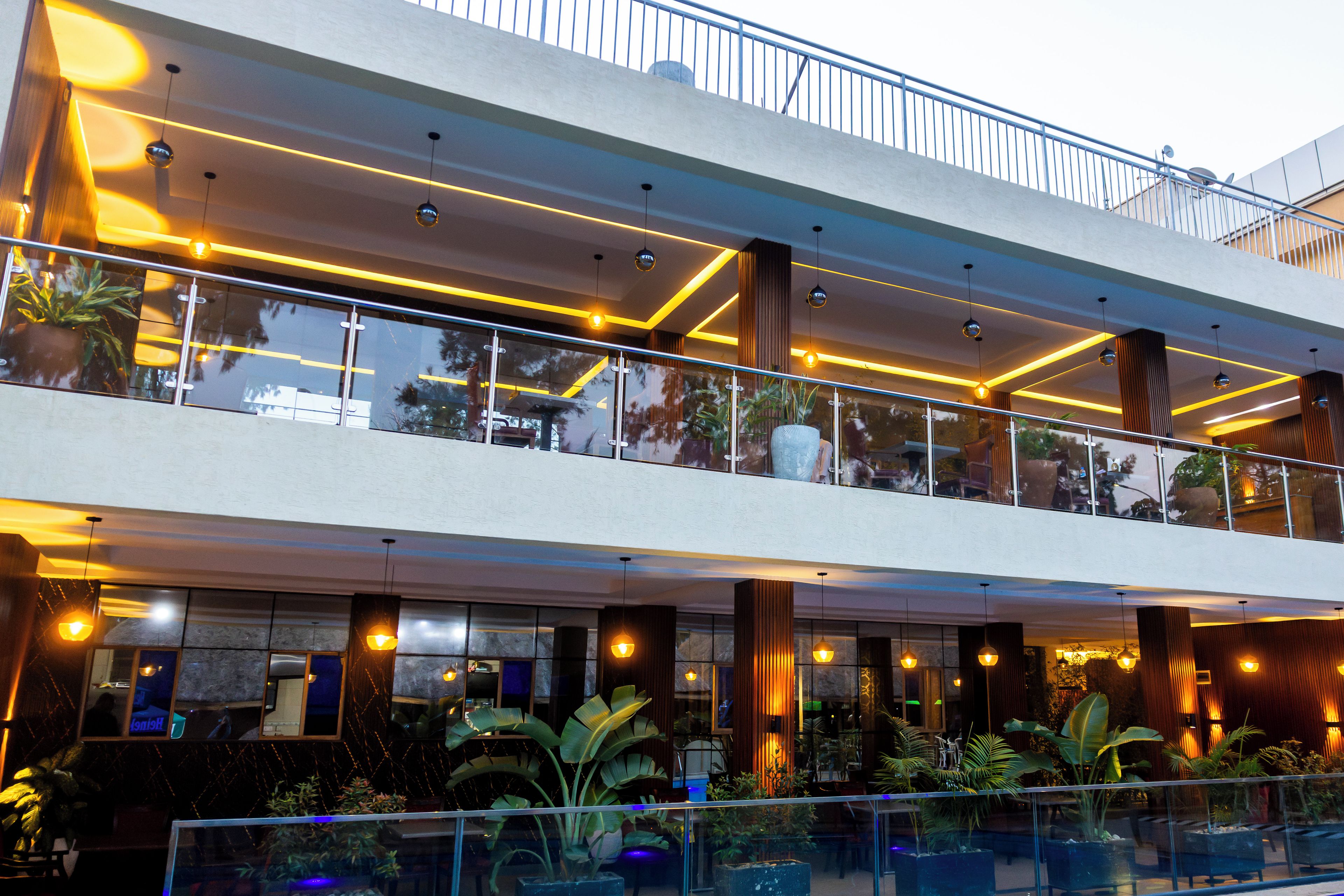 A modern building with a glass balcony, indoor plants, and warm lighting.