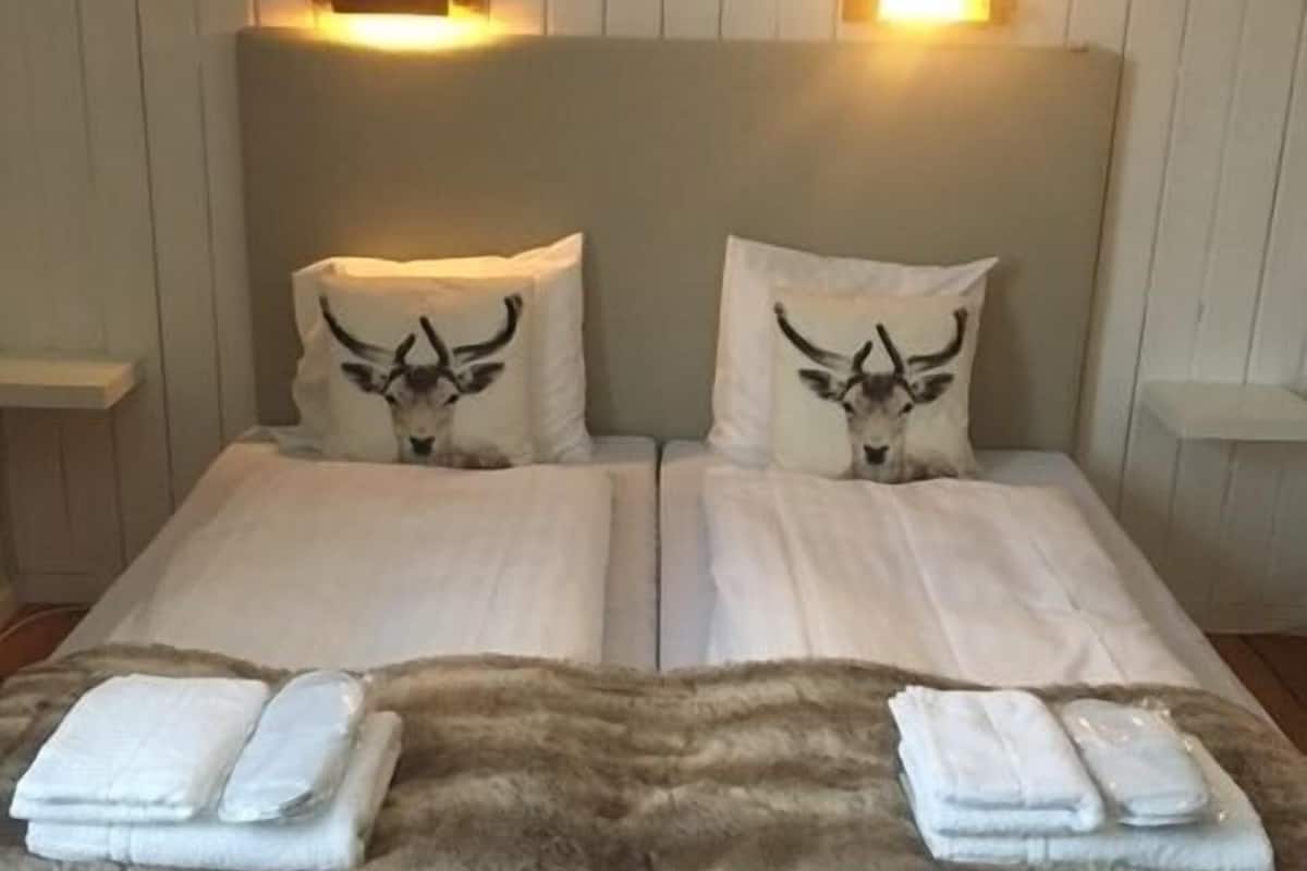 A double bed with two pillows featuring a bull design, a fluffy brown throw blanket, and two bedside tables with lamps.
