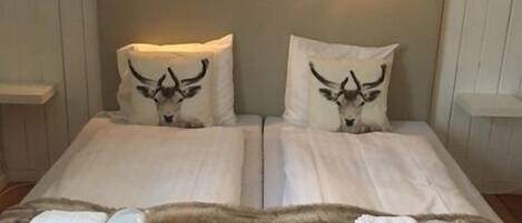 A double bed with two pillows featuring a bull's head design, a fluffy brown rug, and two bedside tables with lamps.