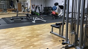A gym with wooden flooring, weightlifting equipment, and a mirror on the wall. - Sonfjällsgården Wärdshus & Hotell (Hede)